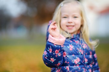 Little girl gathering acorns for crafting and playing on beautiful autumn day