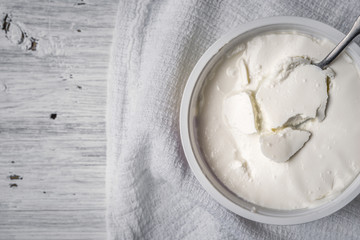 Fresh cheese with spoon and napkin on the white wooden table top view