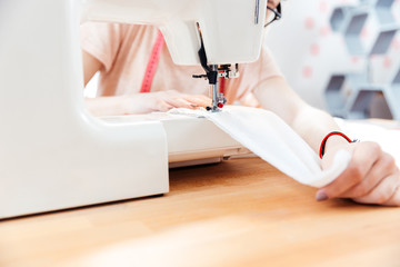 Obraz na płótnie Canvas Seamstress sews clothes using white fabric