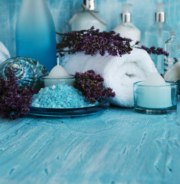 flowers lying on a blue wooden board with shell and candle Spa set