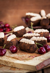 Chocolate rum balls cakes decorated with cream and fresh cherry