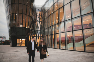 Stylish loving couple kissing and hugging near modern building