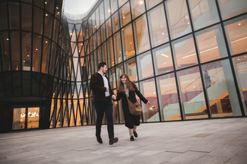 Stylish loving couple kissing and hugging near modern building