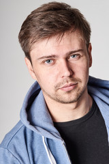 Serious young man with light beard in blue hoodie