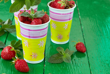 Ripe sweet strawberry and mint leaves on a green painted wooden table