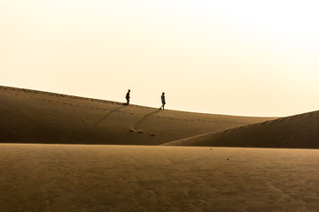 Couple walking in desert on sand dunes