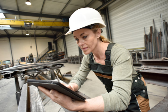 Metalworker woman in factory using tablet