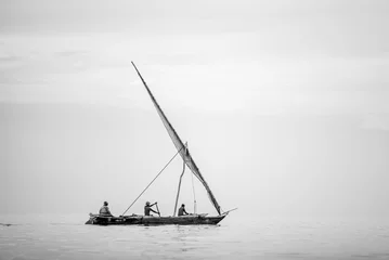 Fotobehang Traditionele Afrikaanse boot die op kalme oceaan vaart © ancamilushev