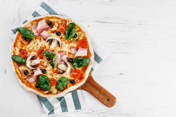 Tasty Italian Hot Pizza on wooden table with mushrooms, basil, tomato, olives and cheese. Look as Prosciutto, Capricciosa, Funghi, Cotto PIZZA. TOP VIEW photo with space for text. 