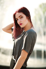 Stylish brown hair girl posing in front of city fountain