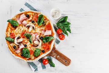 Tasty Italian Hot Pizza on wooden table with mushrooms, basil, tomato, olives and cheese. Look as Prosciutto, Capricciosa, Funghi, Cotto PIZZA with decoration. TOP VIEW photo with space for text. 
