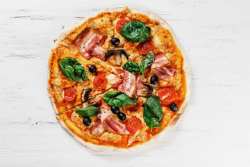 CLOSEUP Tasty Italian Hot Pizza on white wooden table with mushrooms, basil, tomato, olives and cheese. Look as Prosciutto, Capricciosa, Funghi, Cotto PIZZA Photo with space for text. 