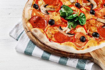 Close-up view of  ITALIAN PIZZA on wooden table. True hot tasty PIZZA with salami, mushrooms, basil, olives, pepper and cheese. Nice for menu Pizzeria. High quality  