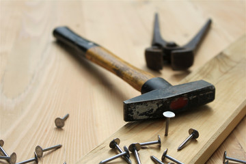 Hammer, pliers and metallic nails. Nail head in focus. Carpentry works.