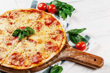 Hot true PEPPERONI ITALIAN PIZZA with salami and cheese. TOP VIEW Tasty traditional pepperoni pizza on board on white wooden table. Copy space for your logo. Ideal for commercial 