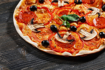 Close-up view of  ITALIAN PIZZA on wooden table. True hot tasty PIZZA with salami, mushrooms, basil, olives, pepper and cheese. Nice for menu Pizzeria. High quality  