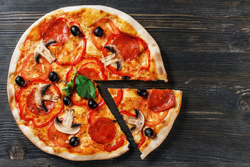 Top view of Italian PIZZA with mushrooms, basil, tomato, olives and cheese. WITHOUT one piece.  Dark wooden table background. Look as Prosciutto, Capricciosa, Funghi, Cotto PIZZA. Ideal for commercial