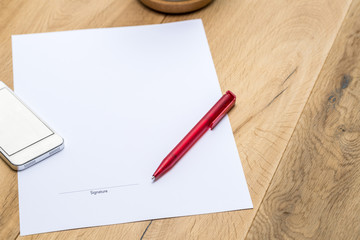 Paper with signature and red pen on desk