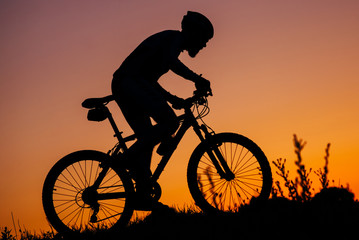 Obraz na płótnie Canvas the young man riding a bike at sunset
