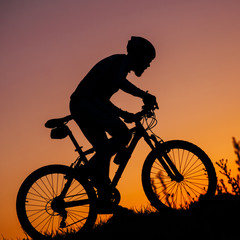 the young man riding a bike at sunset