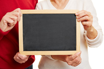 Altes Paar hält leere Tafel mit den Händen