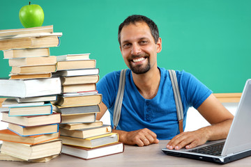 Happy smiling teacher at the classroom working with computer. Photo of smiling teacher, creative concept with Back to school theme