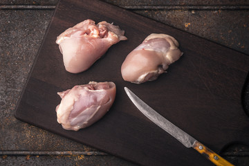 Several chicken thighs without skin on a wooden board