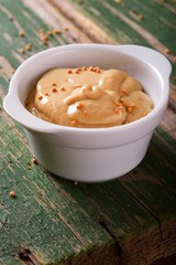 Bowl with mustard on the edge of green wooden table