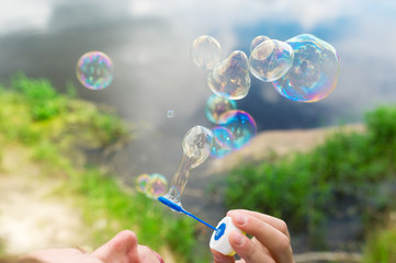 Soap bubbles fly against a beautiful landscape.