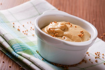 White bowl with mustard  and seeds on green towel