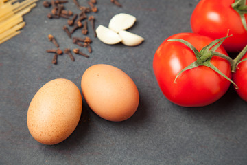 Pasta ingredients. tomatoes, spaghetti pasta, garlic, and tomatoes on dark grunge backdrop. close up