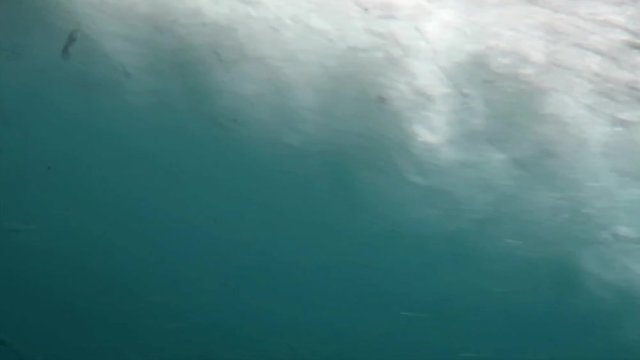 An underwater shot of bubbles passing by the hull of a motor boat as it travels through the ocean