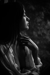 Obraz premium Black and white photography closeup of young pretty woman at the window looking outside