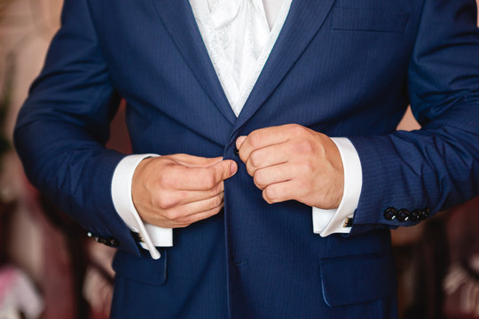 man buttoning a button on his jacket closeup