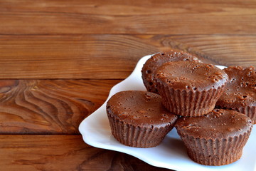 Chocolate muffin. Gourmet dessert. Delicious chocolate cupcakes on a plate on a wooden table. Homemade sweet chocolate cakes