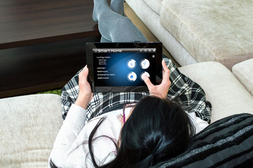 A woman is choosing type of action on tablet's smarthome application at her living room.