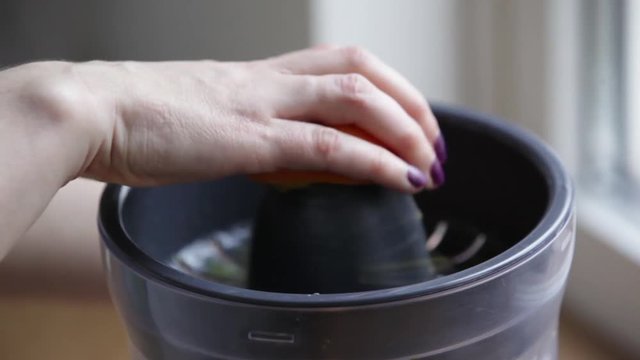 Woman hands preparing orange juice, closeup