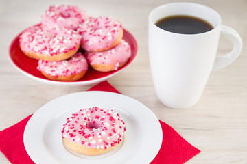 Donuts mit pinker Glasur und einer Tasse Kaffee