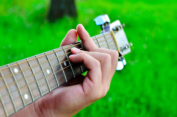 Man plays guitar chords. Men's fingers and guitar strings