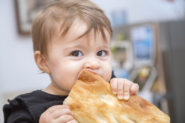 Funny baby girl eating bread