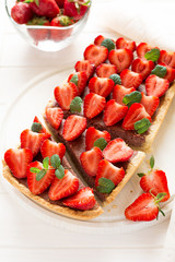 Homemade tart with strawberries and strawberry curd decorated mint leaves on white wooden background