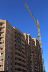 Fototapeta premium beautiful building and a successful businessconstruct highest building of orange brick. standing next to a construction crane. blue sky