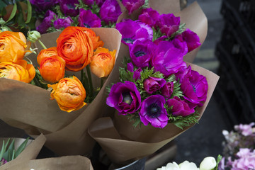 set of violet anemone and orange ranunculus  flowers in bucket