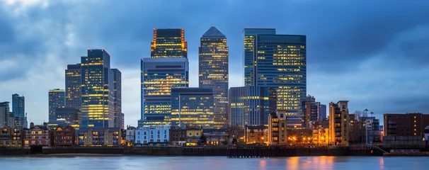 London, United Kingdom - Panoramic view of Canary Wharf, the famous business district with illuminated skyscrapers of London at blue hour © zgphotography