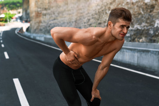 Stomach Ache. Closeup Portrait Of Athletic Man With Fit Muscular Body Touching Belly, Suffering From Abdominal Pain. Handsome Fitness Runner Feeling Bad After Running Outdoors. Sport Injury Concept