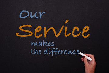 woman writes on blackboard our service makes the difference