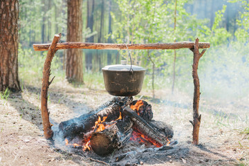 The fire near the camp. Cooking food on a fire. Journey into the wild concept.
