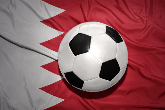 black and white football ball on the national flag of bahrain
