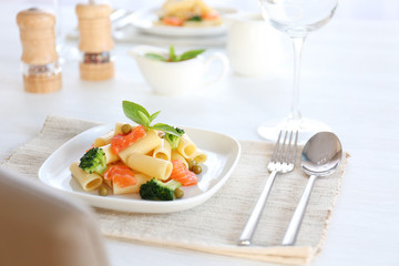 Boiled rigatoni pasta with salmon and broccoli on white plate