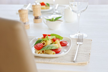 Boiled rigatoni pasta with fresh tomatoes and basil on white plate